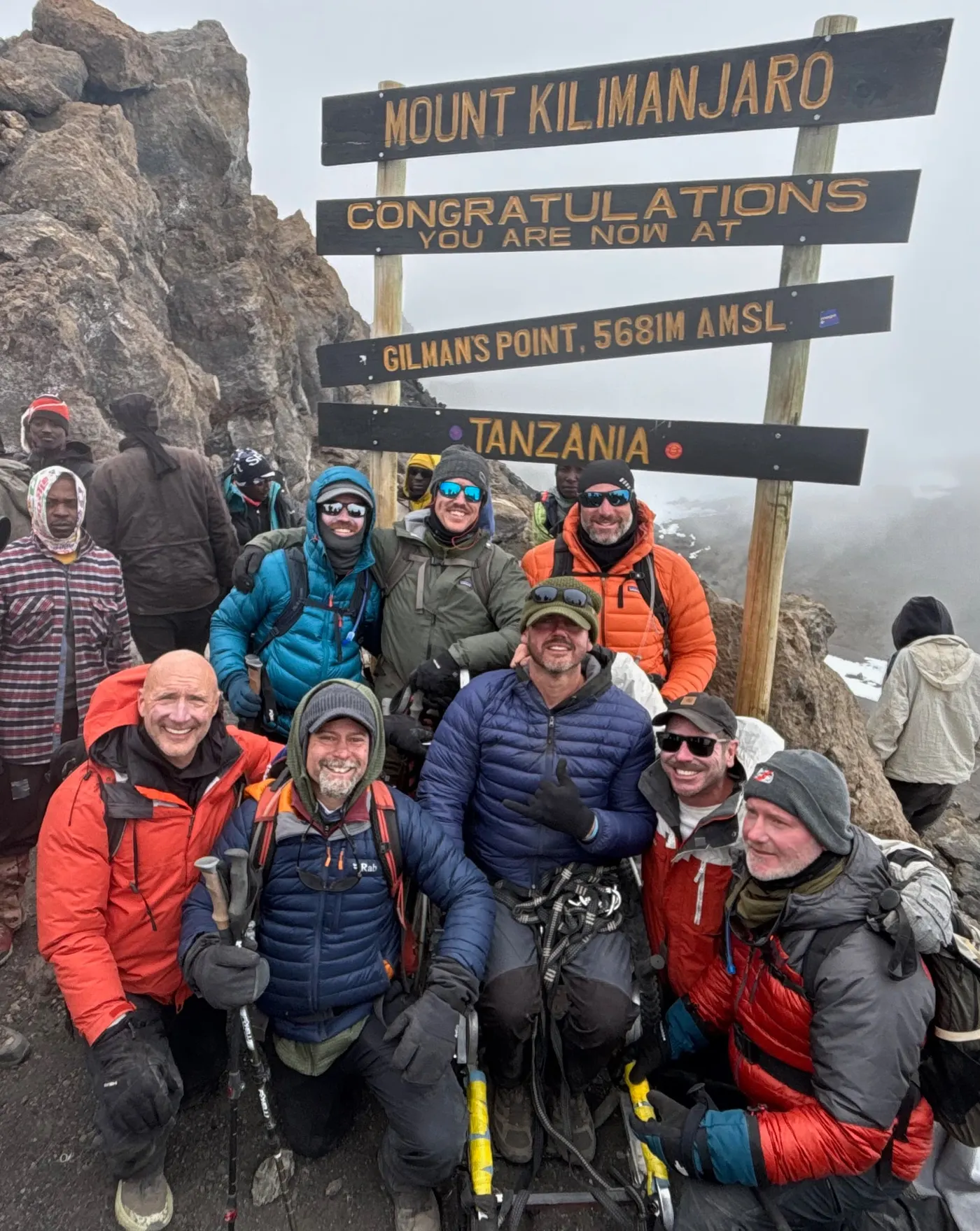 Jeff D. Harmon and his team gathered beneath the Mount Kilimanjaro summit sign in Tanzania